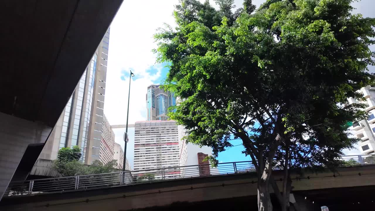 Perspectiva dramática em ângulo baixo do complexo residencial e de escritórios Parque Central, exibindo o contraste entre a arquitetura de concreto e a vegetação tropical.