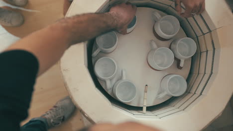 a man and woman using an electric kiln