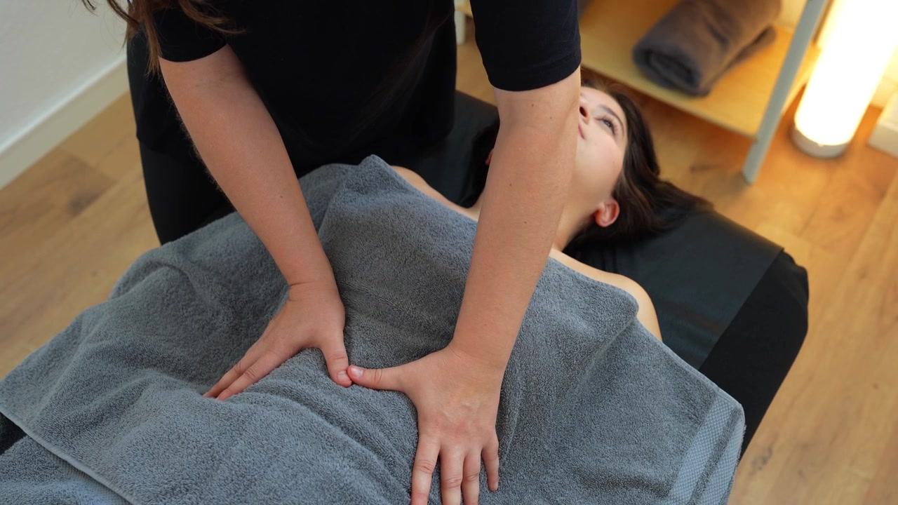 Professionel osteopatisk læge masserer forsigtigt patientens mave under en manuel terapisession.