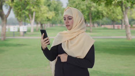 muslim woman talking on video call in park