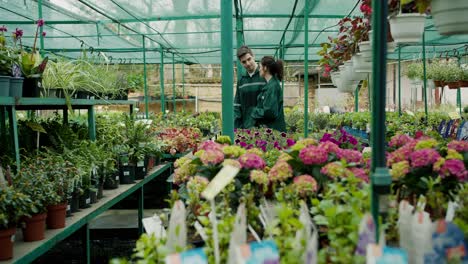 trabajadores de la tienda vestidos de verde caminando y charlando a lo largo de estantes florales