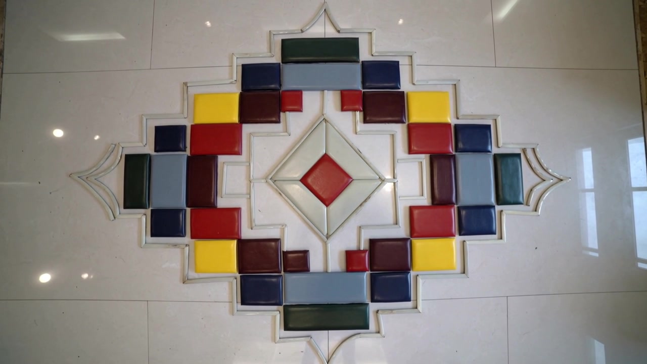 Shifting camera revealing centered tile mosaic at foyer, showing red diamond and light reflections