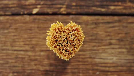 Bunch-of-spaghetti-arranged-in-heart-shape-on-a-wooden-table