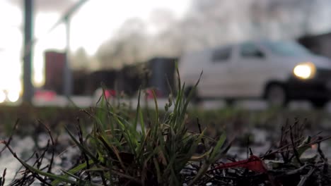 Kleine-Grasfläche-In-Der-Nähe-Der-Straßen-Mit-Verschwommenem-Verkehr-Im-Hintergrund-Und-Nassem-Wetter