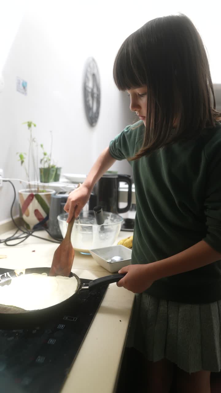 A young girl cooking pancakes