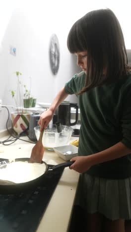 a young girl cooking pancakes