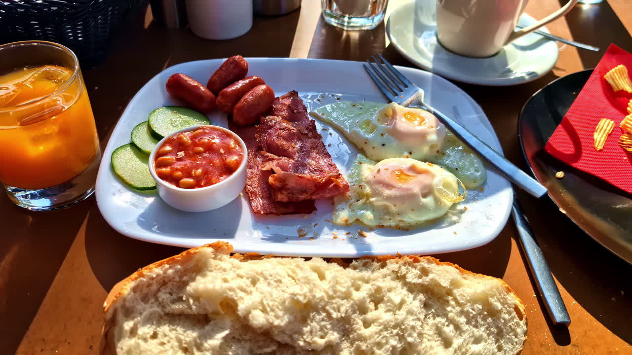 Continental breakfast, eggs bacon baked beans salads and sausage, white plate