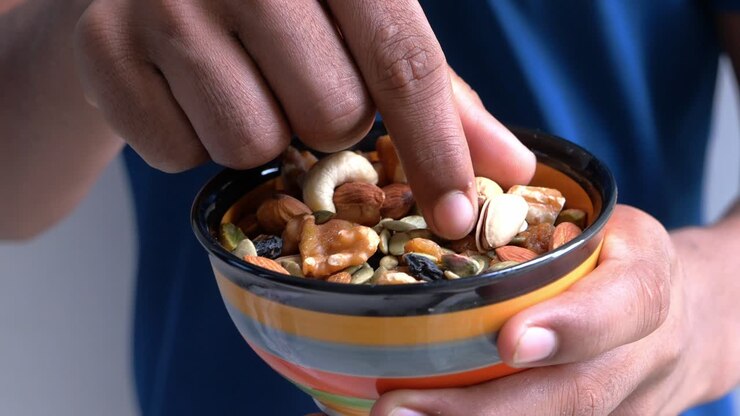 Persona che mangia frutta secca mista da una ciotola
