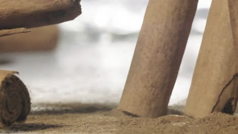 Closeup-shot-Cinnamon-Sticks-Falling-in-slow-motion,-Cinnamon-powder-on-table,-Slow-motion