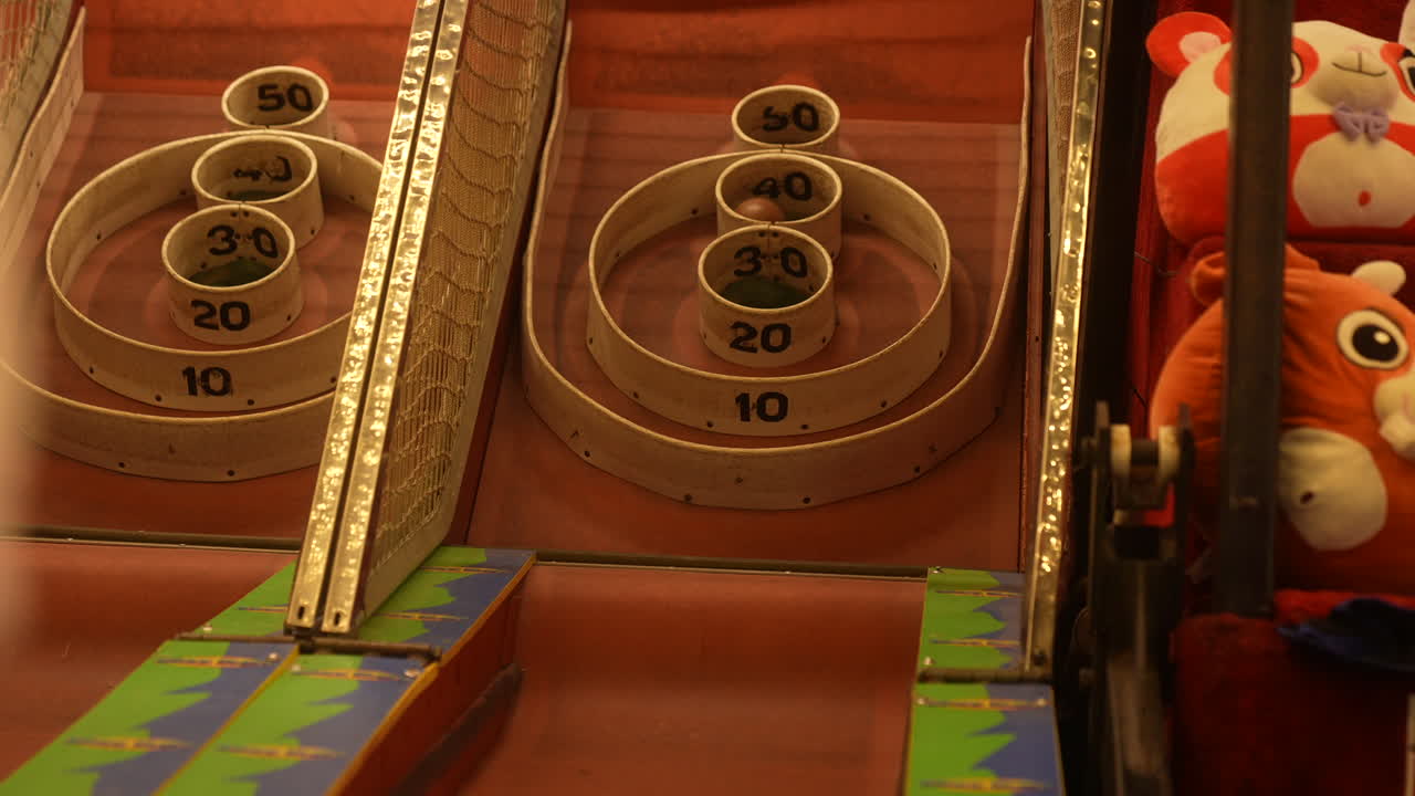Person rolls a skee-ball down the lane at an arcade