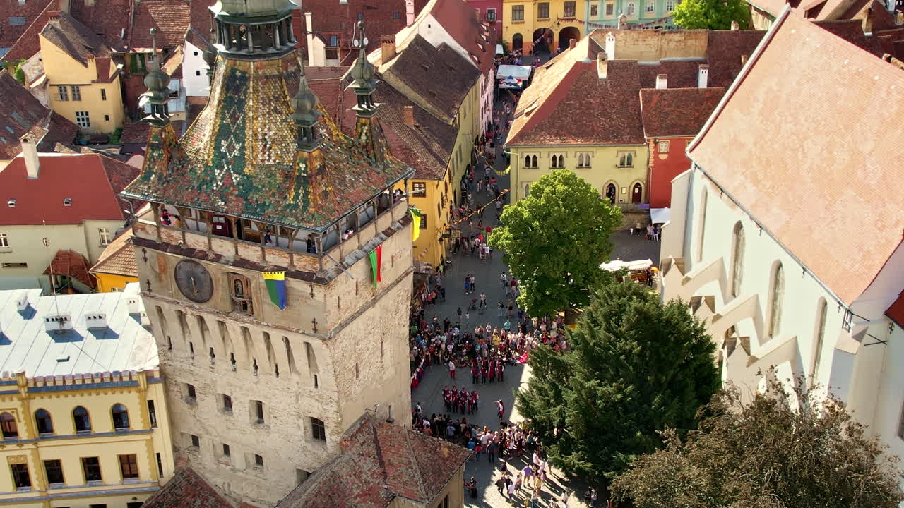 Lotniczy widok z drona na zabytkowe centrum Sighisoary w Rumunii. Stare budynki, wąskie ulice z licznymi ludźmi, Wieża Zegarowa w Sighisoarze