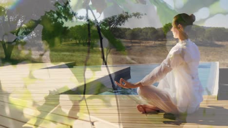 animation of leaves over caucasian woman practicing yoga and meditating