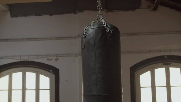 Mezza figura di un sacco da boxe in pelle appeso al soffitto in palestra.