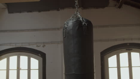 medium shot of leather heavy bag hanging from ceiling in gym