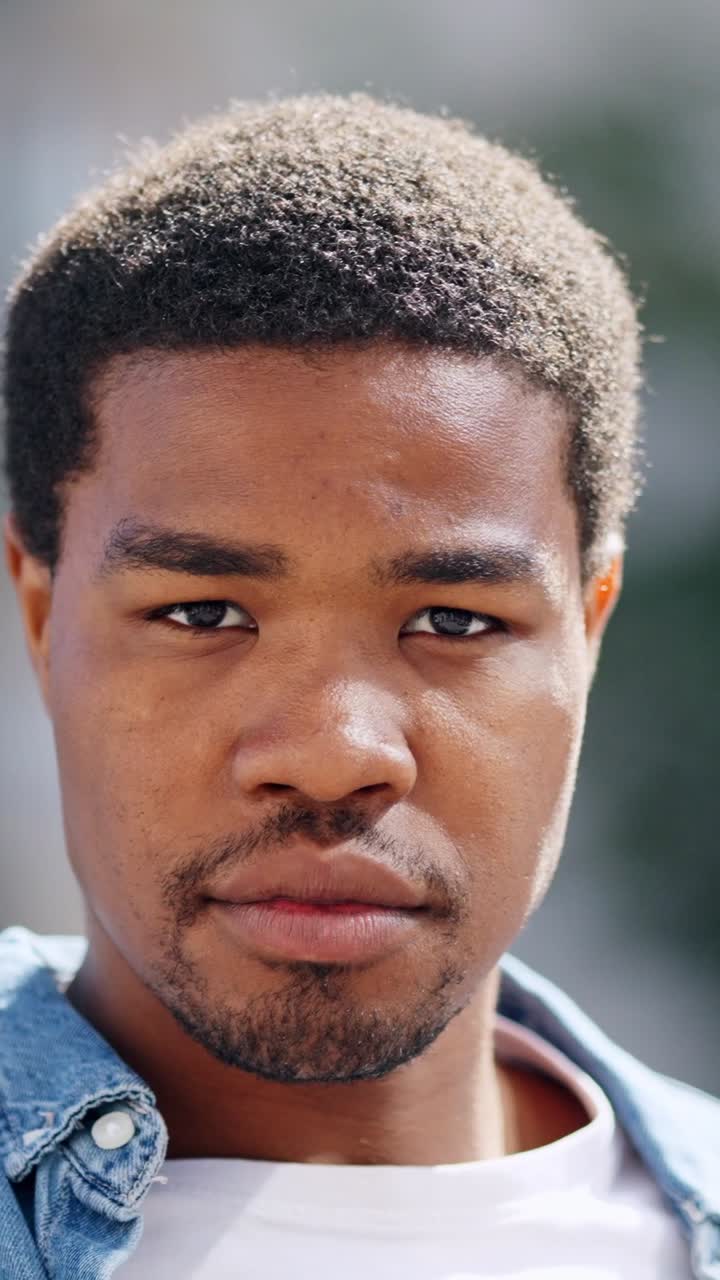 Close-up portrait of a serious young man with a beard looking at the camera
