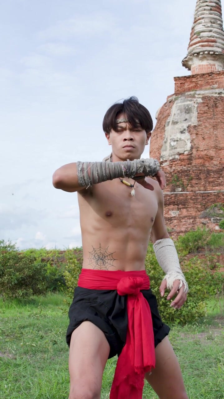 Pugile thailandese esegue movimenti di arti marziali davanti alle rovine di un'antica pagoda ad Ayutthaya, Thailandia.