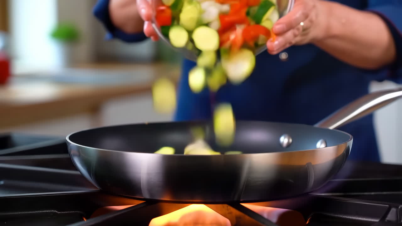 Pouring fresh chopped vegetables into a frying pan