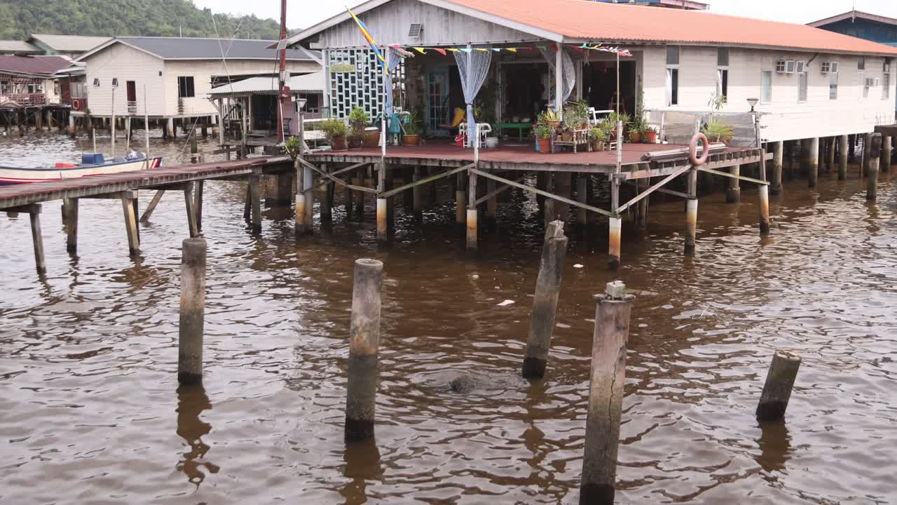 브루나이 다루살람의 반다르 세리 바가완 (bandar seri bagwan) 에 있는 폰 아이어 (kampong ayer) 의 떠다니는 마을에 있는 강변에 있는 기둥집.
