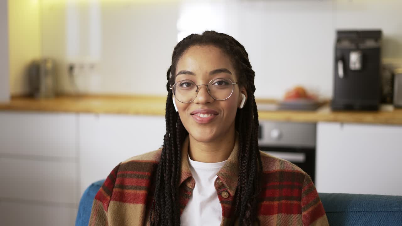 Ritratto di una bellissima donna afroamericana sorridente, felice e fiduciosa, che indossa gli auricolari.