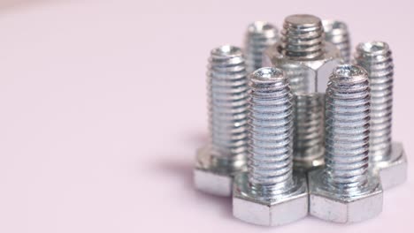 rotating group of galvanized metallic screws close-up. steinless steel bolts isolated on white background.