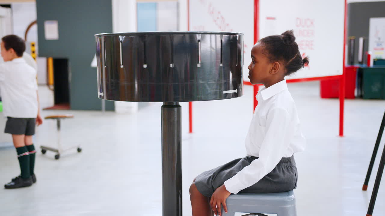 Young black girl using zoetrope at a science activity centre