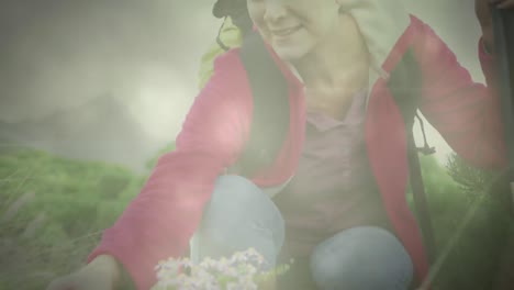 smiling caucasian senior woman hiking and touching plants, over fast moving clouds and sunlight