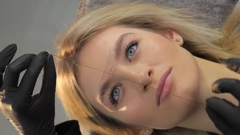 removing unwanted hair from the eyebrows with a thread a cosmetologist does . removing unwanted hair from the eyebrows with a thread, a cosmetologist does,