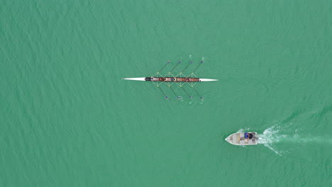 Siguiendo-Un-Entrenamiento-De-Vista-Aérea-Superior-Del-Equipo-De-Remo-Con-Un-Entrenador-En-Un-Lago-En-Barco