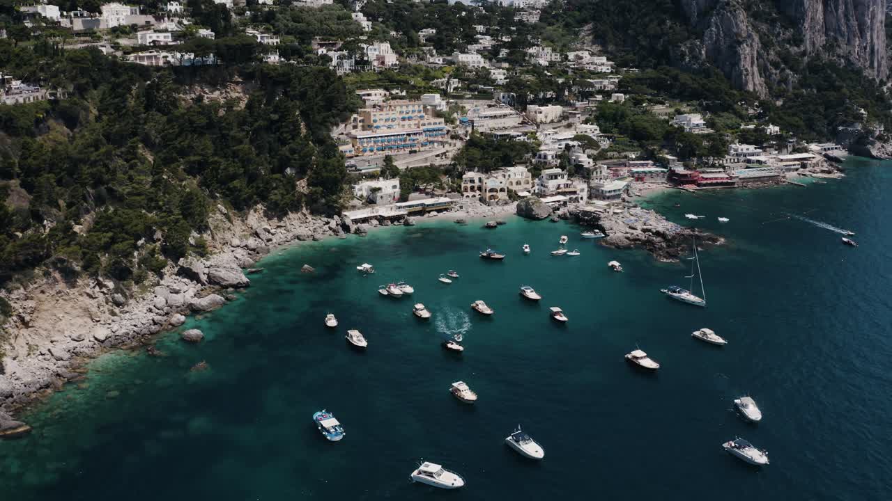 Lowering drone shot of Capri, Italy's boat-filled shoreline