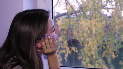 bella adolescente parada junto a una ventana, soñando despierta