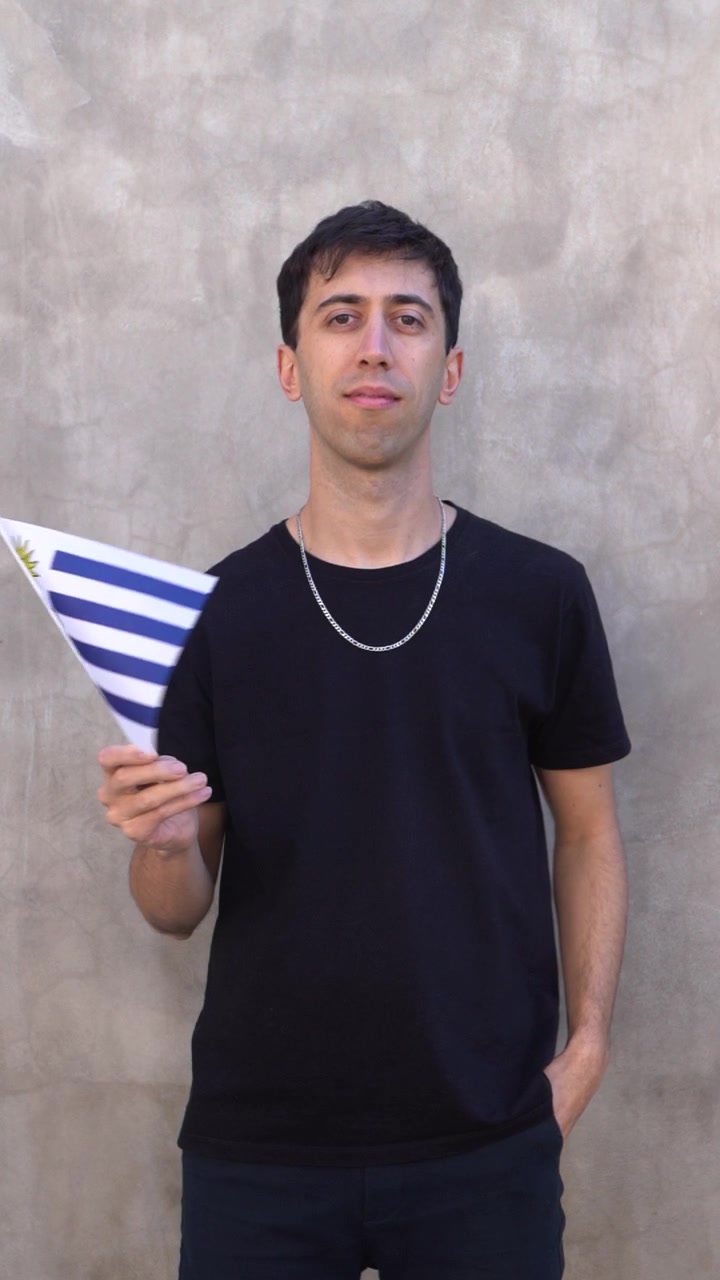 Uomo che sventola la bandiera uruguaiana al rallentatore. Scatto verticale.