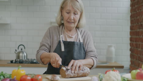 senior woman cutting bread in kitchen