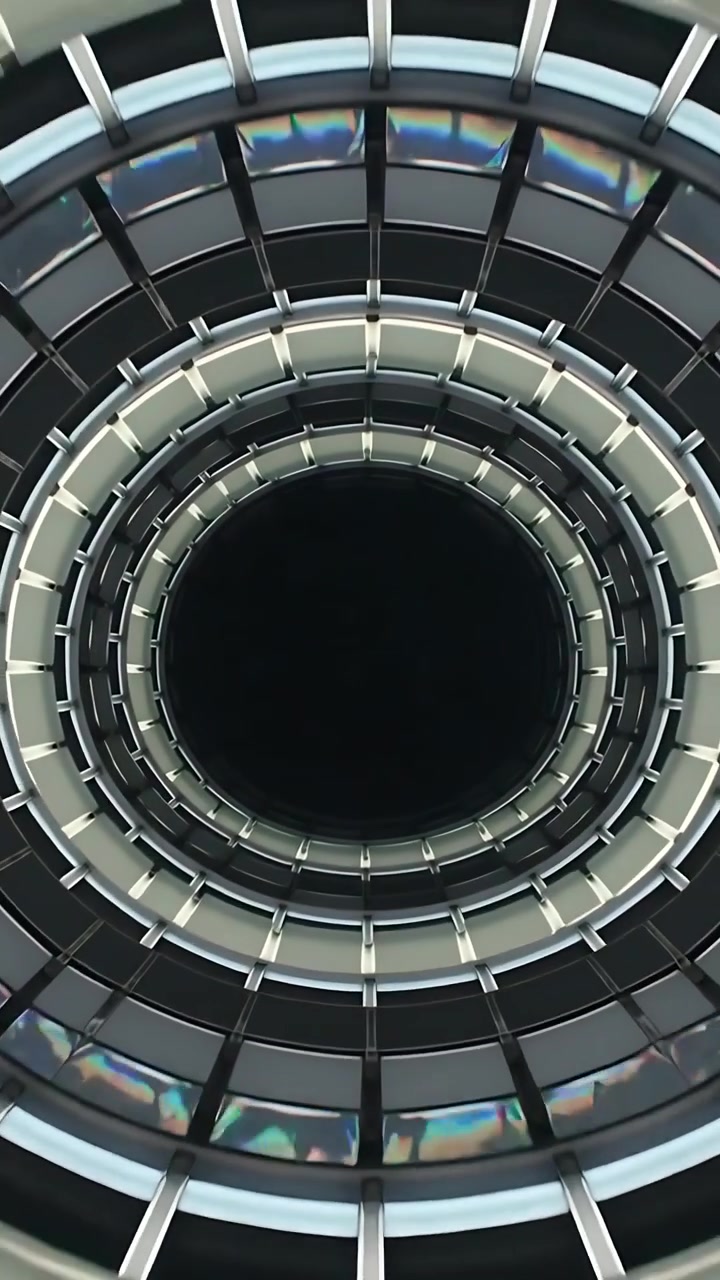Video verticale: L'operatore effettua una panoramica verso l'alto, atrio di un edificio incentrato su un nucleo scuro con anelli e nervature.