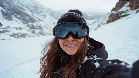 a woman taking a selfie in the snow wearing ski goggles