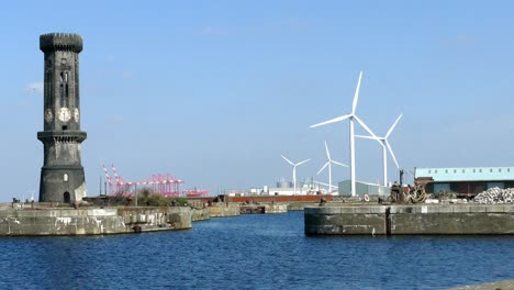 wind-turbines-turning-in-a-port-with-big-cold-clock-tower-camera-zooming-out