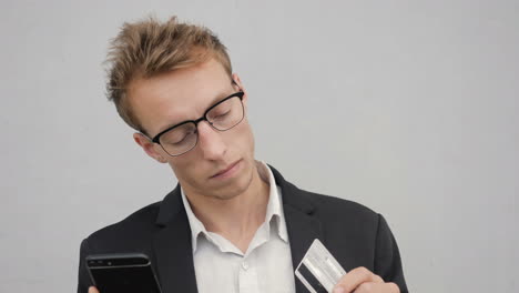 man holding phone and bank card, paying online, thinking