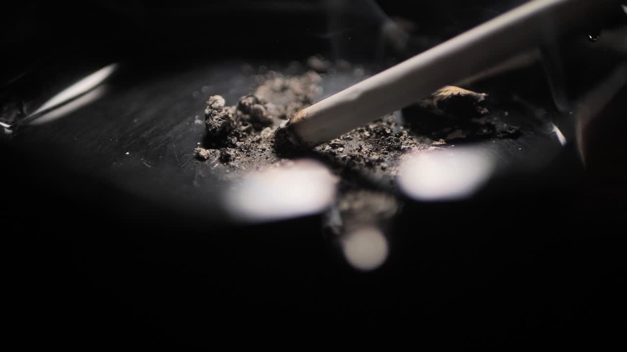 Close up smoking cigarette on man hand.Black ashtray. Scene B