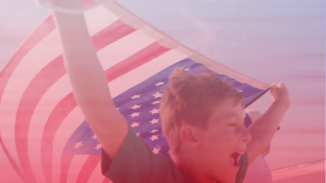 hermano y hermana caucásicos con banderas estadounidenses corriendo en la playa