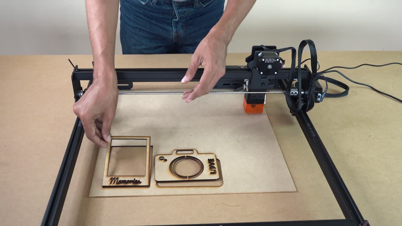 Man displays laser-cut frames with intricate designs, showcasing precision