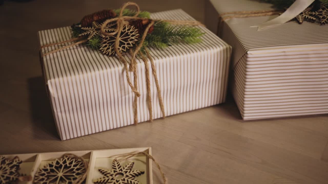 Due regali di Natale incartati in carta a strisce con nastri festivi e rametti di pino - Primo piano.
