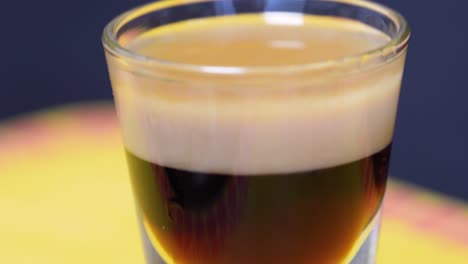 closeup of a shot glass with layered cocktail b52 at the bar counter