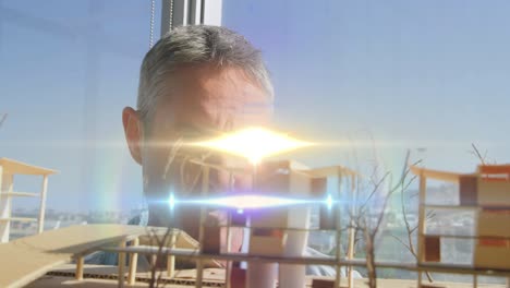 animation of light beams and lens flare over male architect looking at architectural model