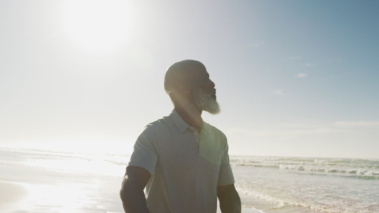 Senior african american man walking with a bicycle at the beach