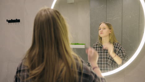 woman checking her appearance in a bathroom mirror