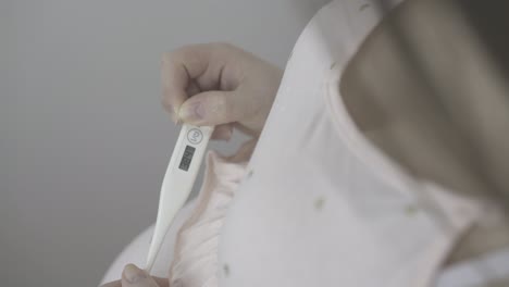 pregnant lady holds modern thermometer with high temperature