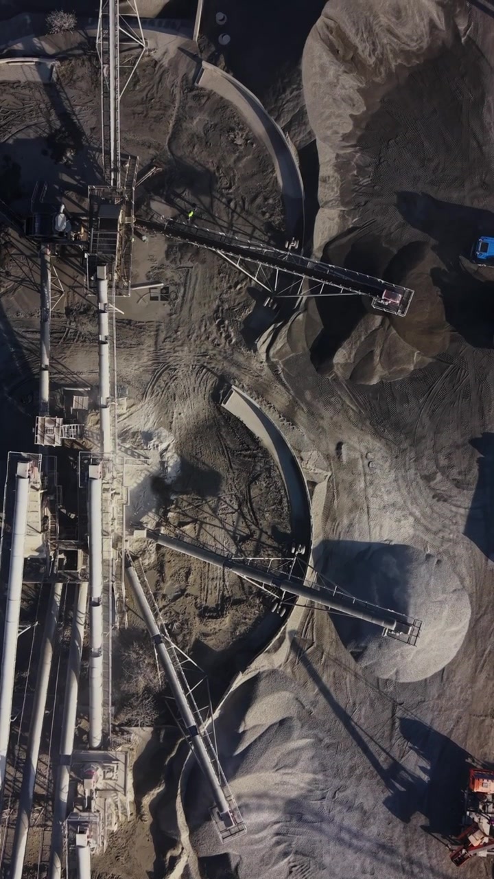 Workers operate machinery at a busy quarry site near a mine