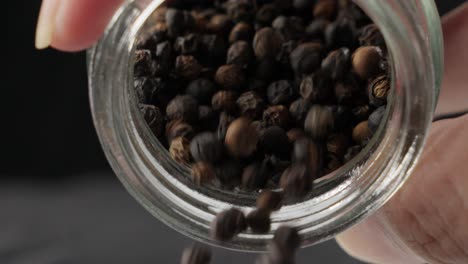 persona que vierte granos enteros de pimienta negra secos