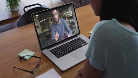mid section of african american woman having a video call with male colleague on laptop