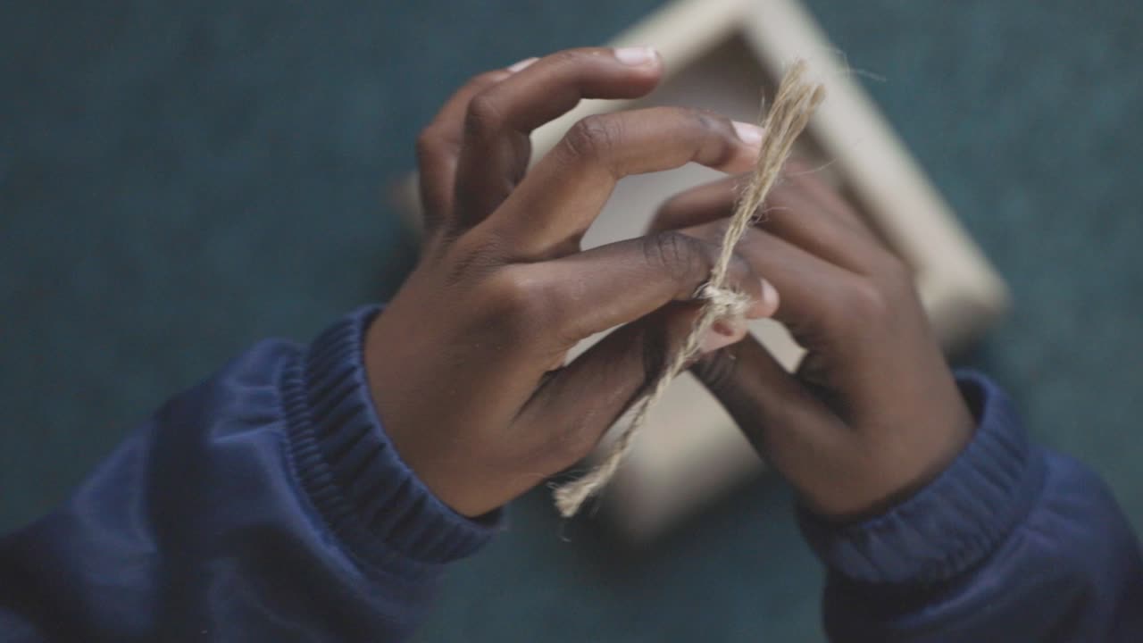 Hands Working with Twine and Tying a Knot