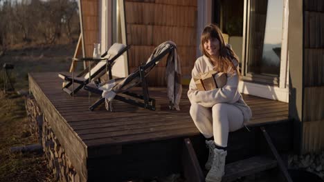 woman sitting on porch with gifts at a cozy winter cabin